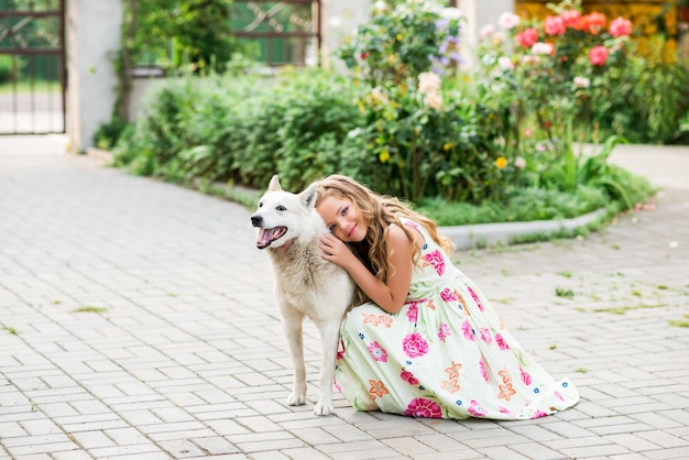 Mädchen umarmt ihren Hund, der schönes Kleid mit einem Hund trägt