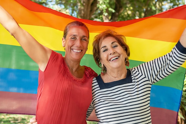 Mädchen und ältere Dame, die die schwule Regenbogenfahne hissen Unterstützung für die homosexuelle Gemeinschaft. Schwulenstolz