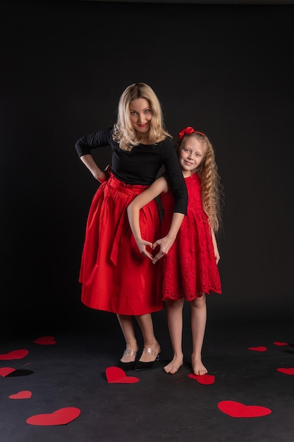 Mädchen und Baby Zeichen der Liebe Hände halten ein glückliches Valentinstag Hintergrund Herz flirten auf dem Boden Herzen Romantik Romantik Form Liebe Formel der Liebe Verlobung in roten Mädchen Kleid barfuß