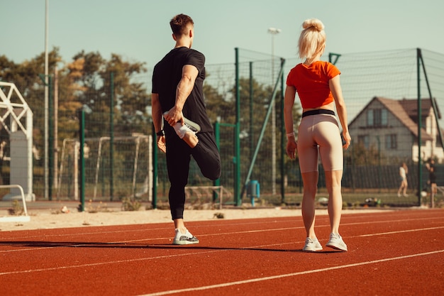 Mädchen und ein Mann machen ein Aufwärmen vor Sportübungen im Schulstadion