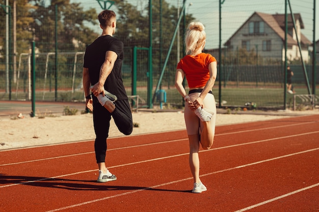 Mädchen und ein Mann machen ein Aufwärmen vor Sportübungen im Schulstadion