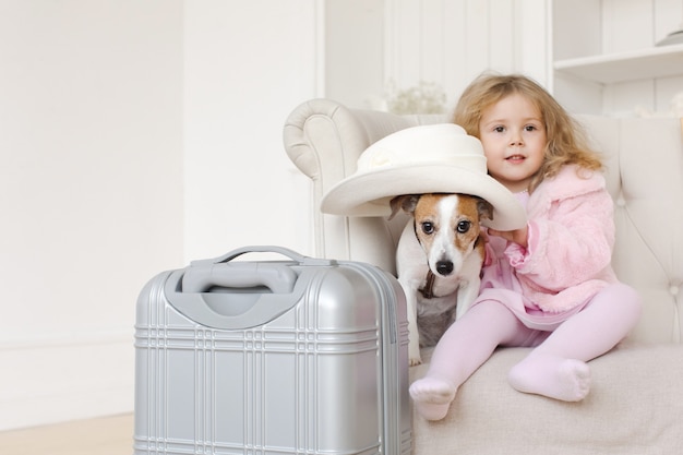 Mädchen und Hund sitzen nahe Koffer