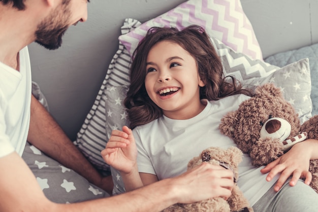 Mädchen und ihr hübscher junger Vati halten Teddybären.