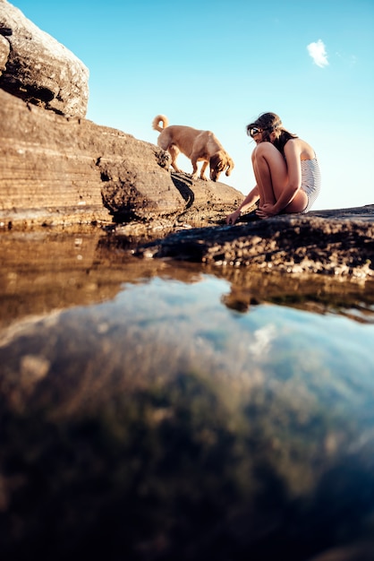 Mädchen und ihr Hund, die felsigen Strand erforschen