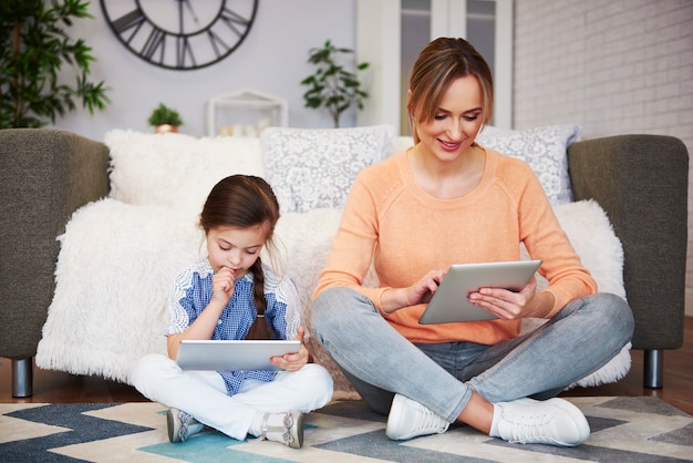 Mädchen und ihre Mutter mit einem Tablet im Wohnzimmer