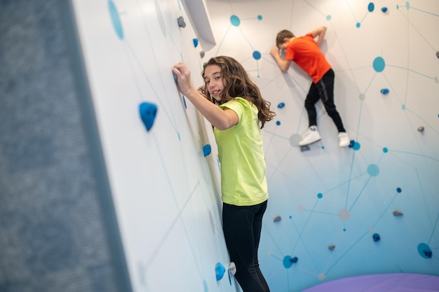 Mädchen und Junge, die an der Indoor-Kletterwand hängen