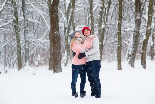 Mädchen und Junge, die Schneeflocken im Winterwald fangen