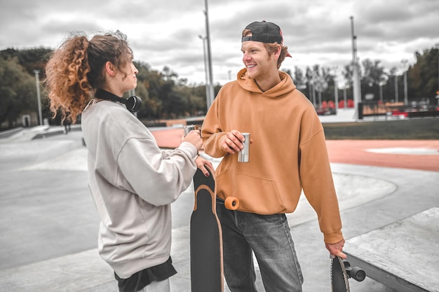 Mädchen und Kerl-Skateboarder chatten nach dem Training