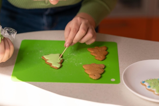 Foto mädchen verziert lebkuchen mit zuckerglasur frohe weihnachten und guten rutsch ins neue jahr-konzept