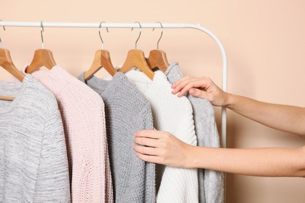 Mädchen wählt einen warmen Pullover aus der Garderobe des Kleiderbügels