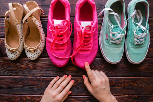 Mädchen wählt Schuhe auf einem hölzernen Hintergrund