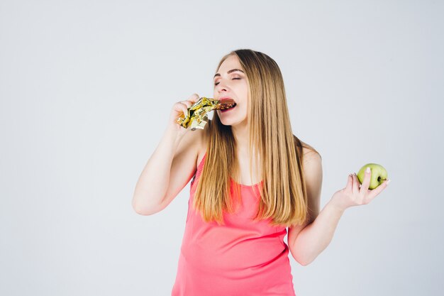 Mädchen wählt zwischen Apfel und Schokolade