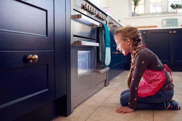 Mädchen warten am Ofen in der Küche zu Hause auf Kuchen zum Backen