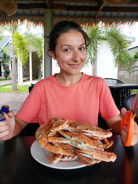 Mädchen wird gekochte Krabben essen. Mädchen am Tisch mit einem vollen Teller mit gekochten blauen Krabben.