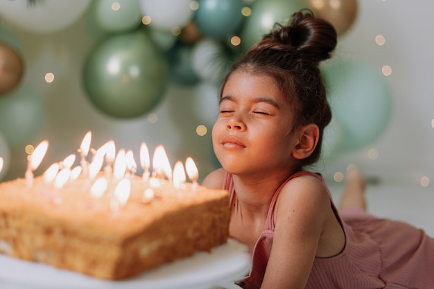 Mädchen wünscht sich und bläst die Kerzen auf der Geburtstagstorte aus Süßes Mädchen, das ihren Geburtstag feiert