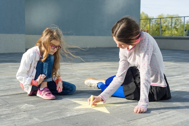 Mädchen zeichnen auf das asphaltfarbene buntstiftsymbol