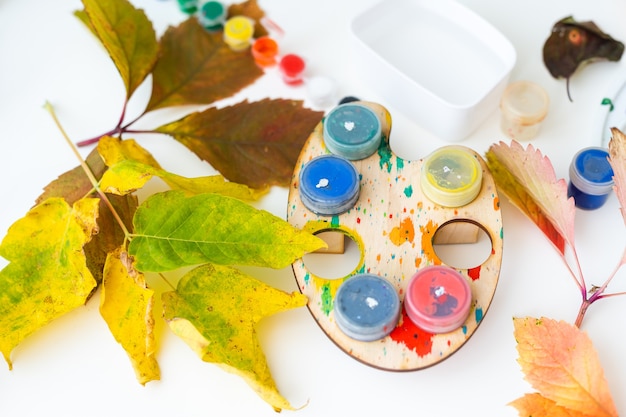 Mädchen zeichnen mit Farbe auf Herbstlaub am Tisch.