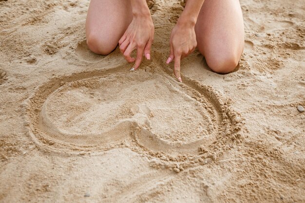 Mädchen zeichnet Herz in den Sand