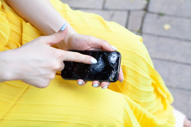 Mädchen zeigt auf kaputtes Telefon im Park