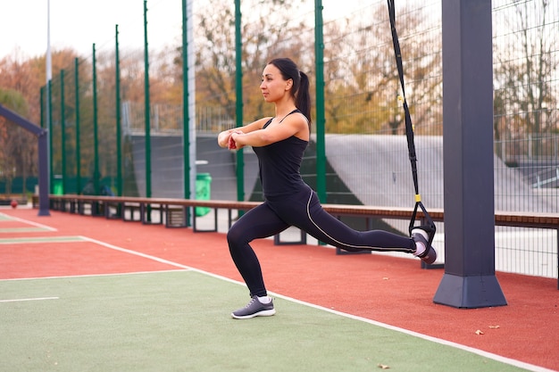 Mädchenathletentraining mit trx auf Sportplatz