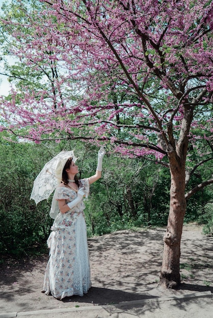 Mädchenbraut im Weinlesekleid nahe blühendem Baum