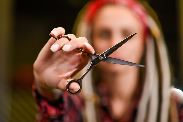 Mädchenfriseur mit den Dreadlocks, die in der Hand Nahaufnahme der Scheren halten