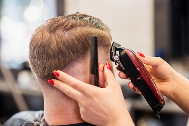 Mädchenfriseur trocknet einem Mann in einem Salon Haar