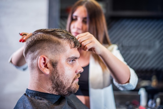 Mädchenfriseur trocknet einem Mann in einem Salon Haar