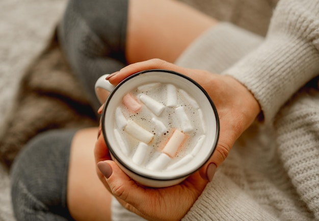 Mädchenhände, die einen mit Kakao und Marshmallow gefüllten Becher halten Gemütliches Nahaufnahmeporträt einer Frau mit warmem Getränk in der Tasse im Winter