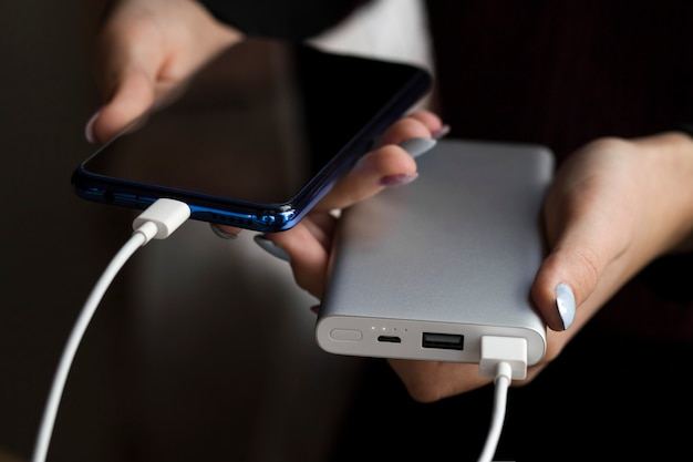 Mädchenhände halten Telefon und Ladegerät Powerbank und Smartphone in Mädchenhänden Powerbank