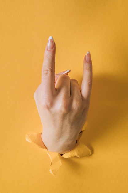 Mädchenhand bricht das gelbe Papier und zeigt eine Geste