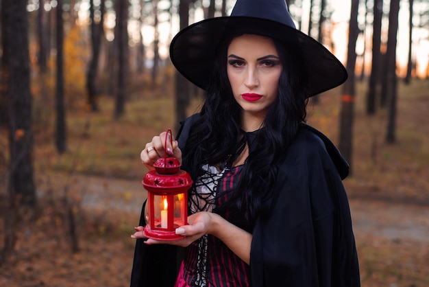 Mädchenhexe mit einer Taschenlampe im Wald an einem Herbstabend an Halloween