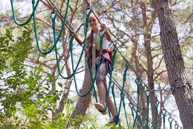 Mädchenjugendlicher mit kletternder Ausrüstung in einem Seilunterhaltungspark