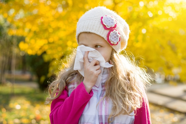 Mädchenkind mit kalter Rhinitis auf Herbsthintergrund