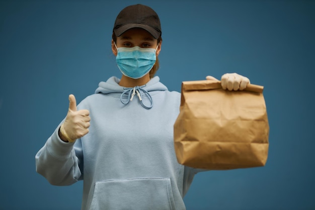 Mädchenkurier in einer medizinischen Maske und medizinischen Handschuhen auf blauem Hintergrund