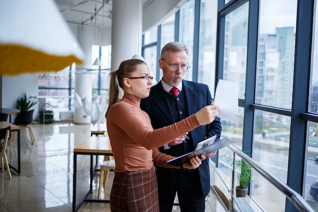 Mädchenmanagerin in ihrem eigenen Büro erzählt ihrem Lehrer-Mentor-Chef einen erfolgreichen neuen Geschäftsplan für die wirtschaftliche Entwicklung. Hält einen Ordner mit wichtigen Dokumenten in den Händen.