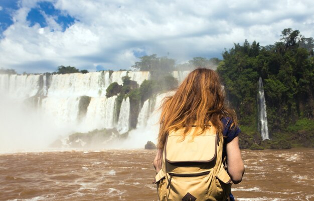 Mädchentourist betrachtet den Blick auf die weltweit bekannten Iguazú-Wasserfälle an der Grenze zwischen Brasilien und Argentinien