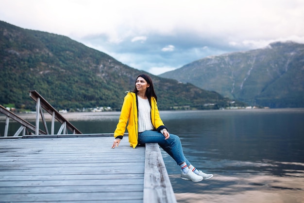 Mädchentourist in der gelben Jacke, die auf dem See in Norwegen aufwirft Aktive Frau, die in Norwegen sich entspannt