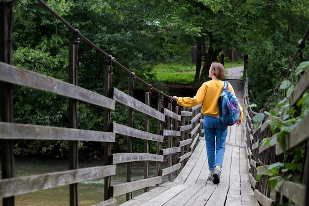 Mädchenwanderer mit Rucksack auf der Hängebrücke stehend