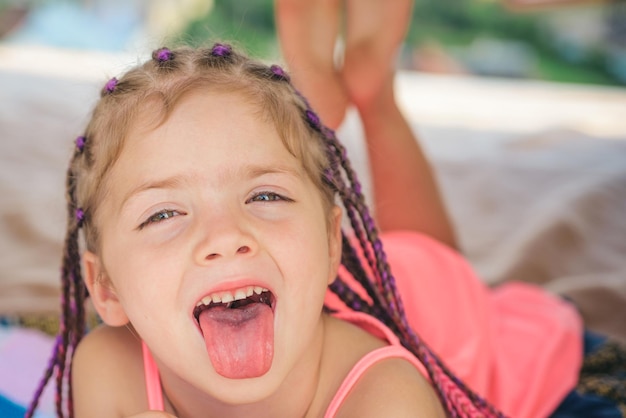 Mädchenzunge raus. Spaß im Freien haben. Campingplatz. Lächelndes entzückendes Kind im Lager. Kind, das im Zelt spielt. Kindercamping.