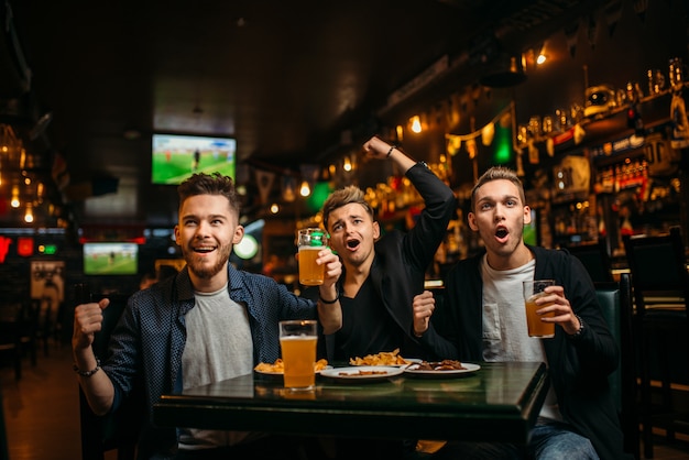 Männer am Tisch mit Bier, Chips und Crackern