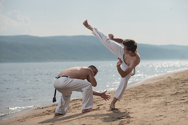 Männer bilden capoeira auf dem Strand aus - Konzept über Leute, Lebensstil und Sport.