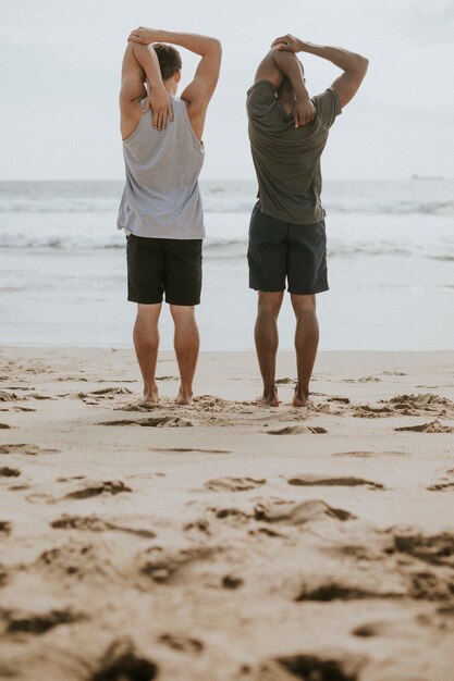 Männer dehnen sich am Strand