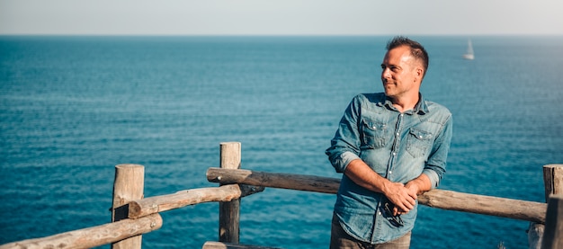 Foto männer, die das denimhemd bereitsteht das meer und erwägt tragen