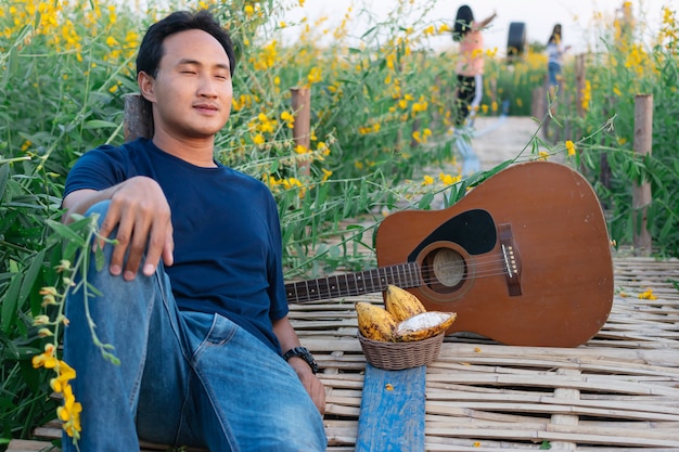 Männer, die Gitarre in der schönen Sunhempblume im Garten spielen