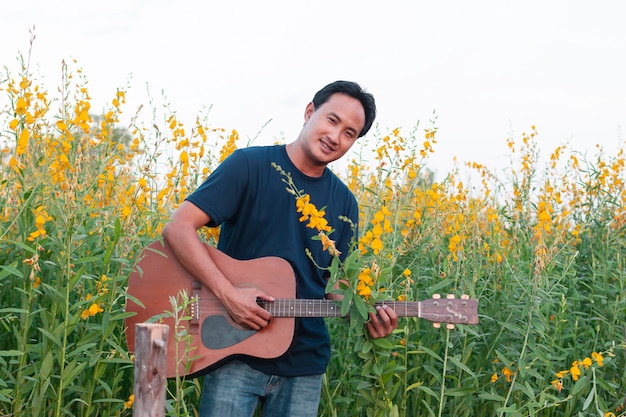 Männer, die Gitarre in der schönen Sunhempblume im Garten spielen