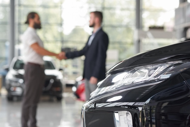 Foto männer, die hände im modernen autohaus rütteln