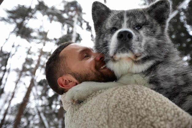 Männer, die mit sibirischem Husky im Winterwald spielen und Parktiere und Ökologie Haustierliebhaber Konzept des Freundes des Hundemenschen