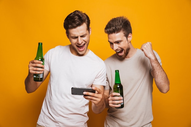 Männer Freunde, die Handy benutzen, machen Gewinnergeste.