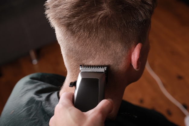 Männer Haarschnitt, schneidet der Meister den Mann mit einem Haarschneider, Friseurwerkzeug.